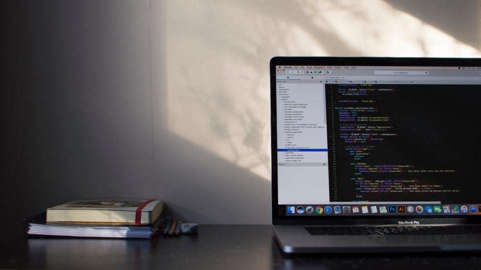 A laptop showing code on a sunlit desk