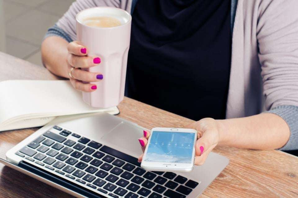 Checking business email on a phone beside a laptop