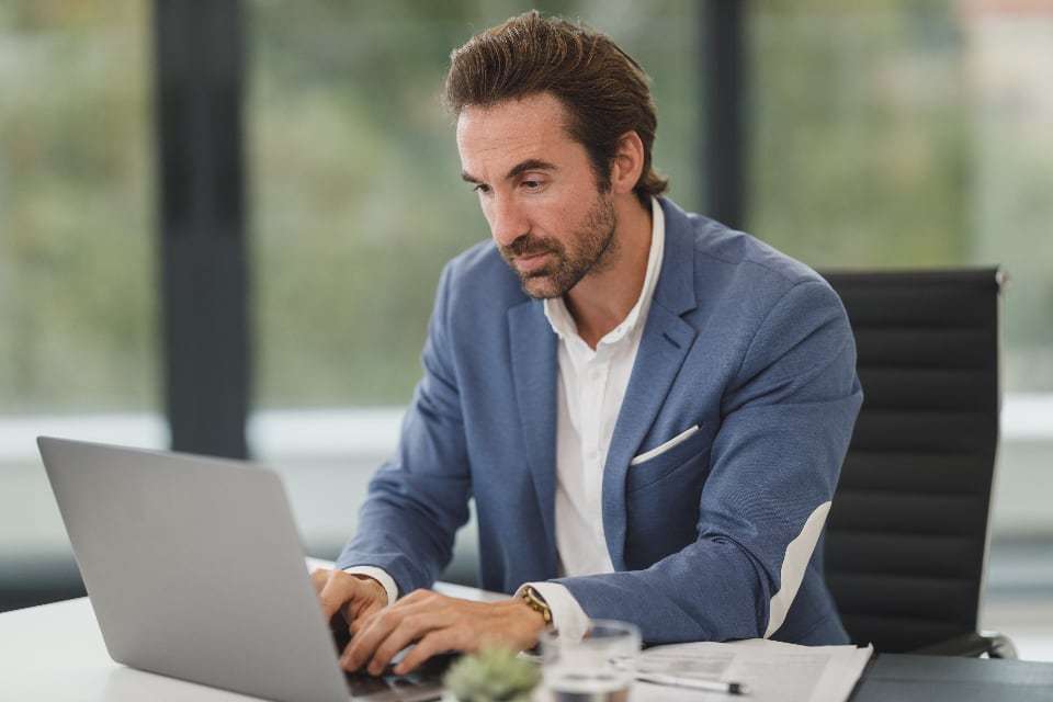 A business owner working on a laptop in a bright, modern office