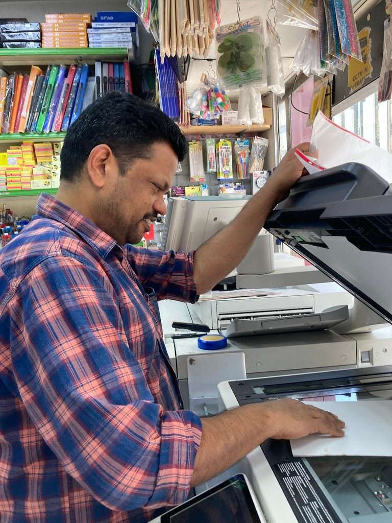 A print shop owner loading paper into a professional printer