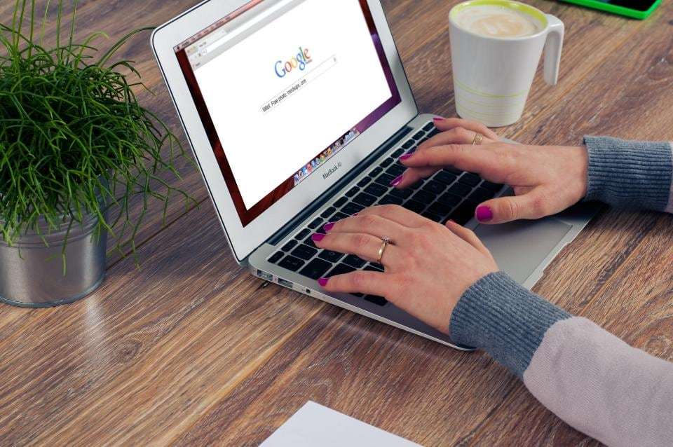 Searching the web on a laptop at a wooden desk