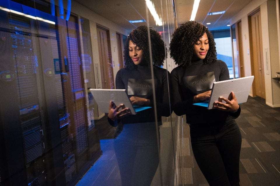 A technician with a laptop in a server room corridor